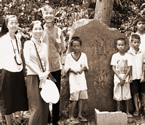 写真をクリックすると新聞切抜き記事へリンク。写真＝集まってきた周辺部落の子どもたちも加わり慰霊塔の前で記念撮影する筆者夫妻（左から2,3人目）＝3月1日、フィリピン・レイテ島